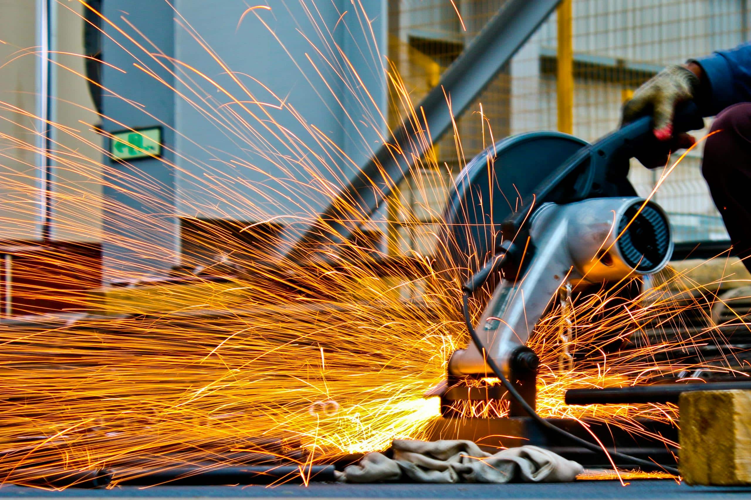 a worker operates a grinder cutting metal creating a vibrant display of sparks in an industrial setting. 1145434 scaled, TAG: Employment and HR Solutions