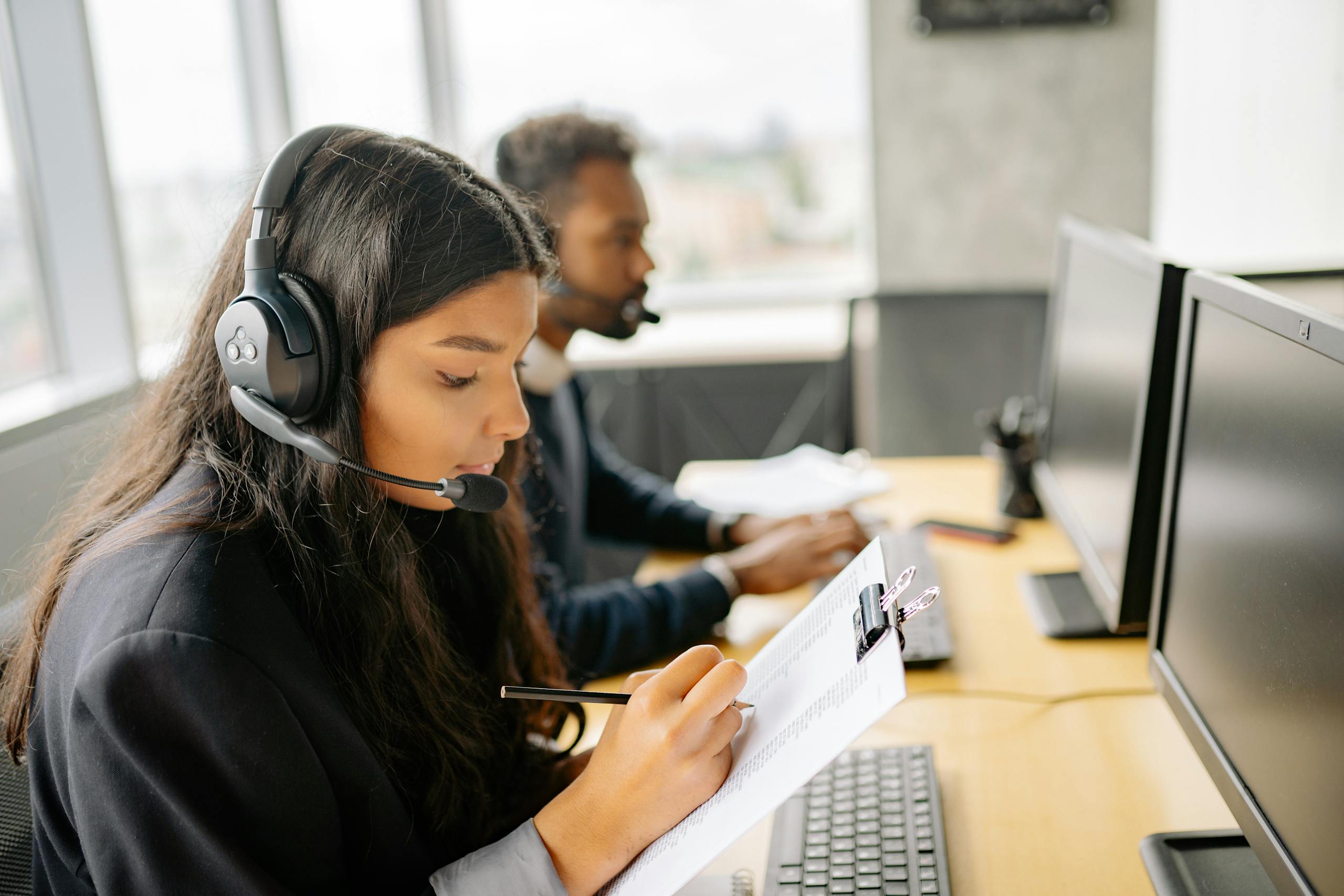 two call center agents wearing headsets working at desks with computers in a modern office. 8867429 scaled, TAG: Employment and HR Solutions