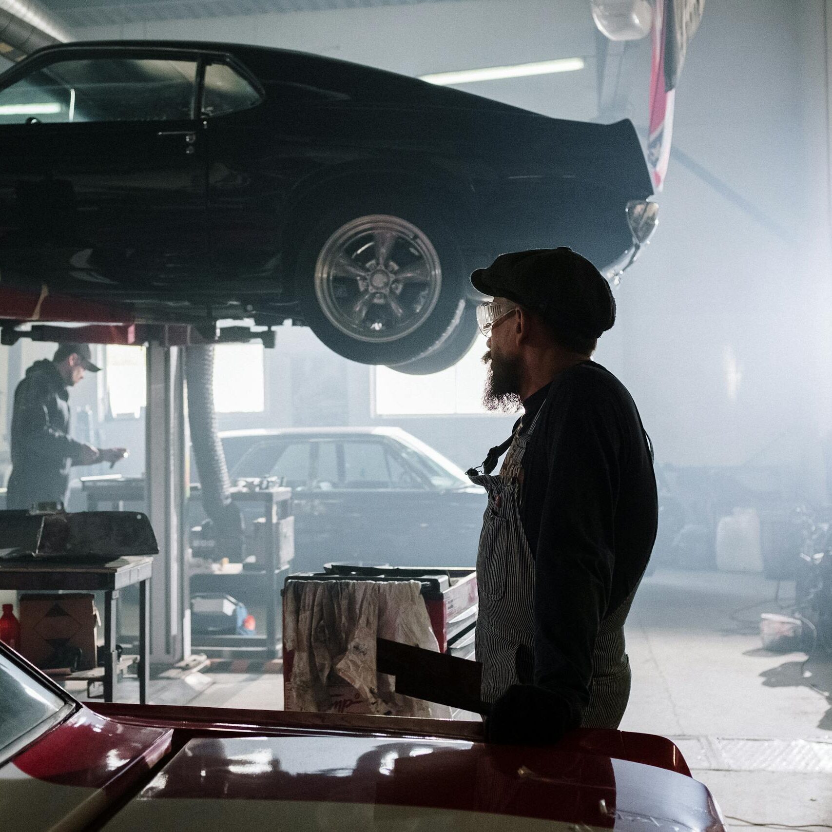 mechanics busy at work in a dimly lit auto repair garage with a raised car. 4489708 scaled e1738336024852, TAG: Employment and HR Solutions