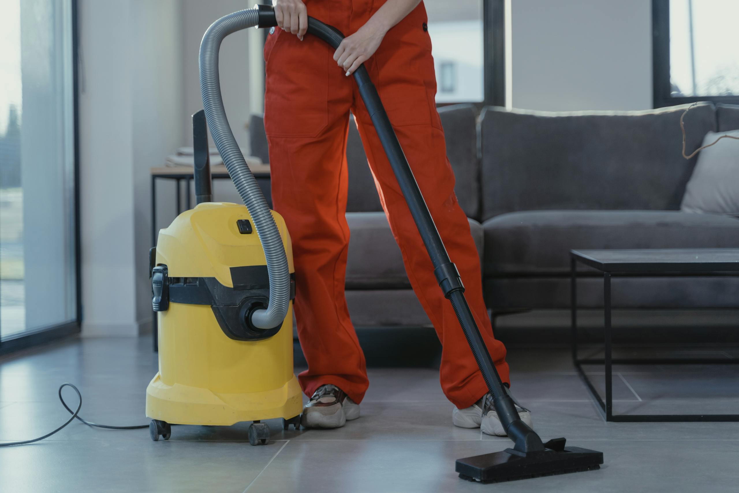 a professional cleaner in red coveralls vacuums a contemporary living room with a yellow vacuum cleaner. 6195273 scaled, TAG: Employment and HR Solutions